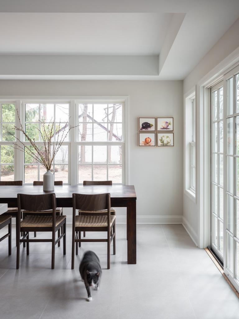 Bogert Home dining area — walnut dining table framed by tall windows and French doors, with four framed botanical prints on the wall