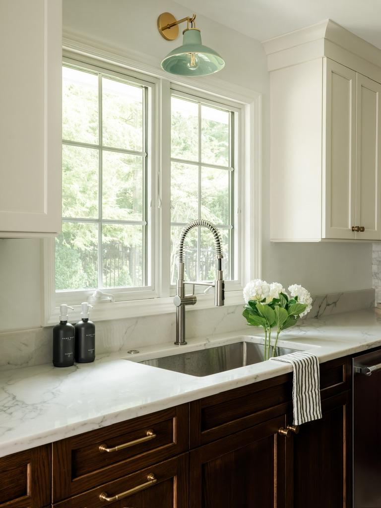 Monte Vista — kitchen sink beneath twin windows with a stone counter and brass hardware